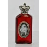 A SILVER CAPPED RUBY GLASS FACETTED SCENT BOTTLE, having a screw fit cap fashioned as a crown, and