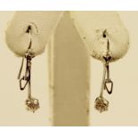 A PAIR OF DIAMOND AND WHITE GOLD COLOURED METAL SET DROP EARRINGS each having a claw set stone