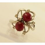 A MODERNIST RUBY AND DIAMOND DRESS RING having two cabochon rubies and six satellite 8/8 cut