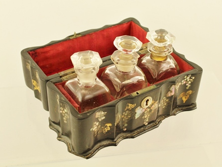 A LATE 19TH CENTURY PAPIER MACHE BOX containing three scent bottles with stoppers, casket is