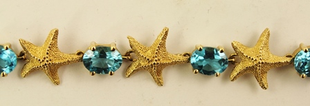 A MODERN GOLD COLOURED METAL BANGLE of alternating five point starfish and oval claw, set blue topaz - Image 4 of 4