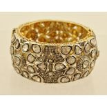 A DIAMOND MOUNTED WHITE AND GOLD METAL SET BANGLE having sixty substantial flat cut diamonds