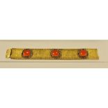 A BROAD GOLD COLOURED METAL BRACELET of floral engraved and bright cut links set with three