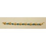 A MODERN GOLD COLOURED METAL BANGLE of alternating five point starfish and oval claw, set blue topaz