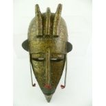 A POSSIBLY AFRICAN TRIBAL MASK, having allover nailed metal sheeting, 34cm high