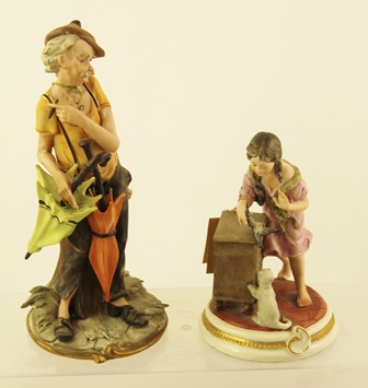 TWO CAPO-DI-MONTE PORCELAIN FIGURINES one signed by Nico Venzo, depicts a man with parasols, 26cm
