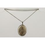 A 1970/80'S OVAL SILVER COLOURED METAL LOCKET with bright cut decoration on box link period chain