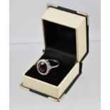 A RHODIUM FINISHED WHITE GOLD COLOURED METAL DRESS RING, set with a single faceted ruby bordered