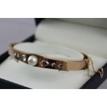 A VICTORIAN STYLE ROSE GOLD BANGLE, set with cultured pearl flanked by six graduated multi-faceted