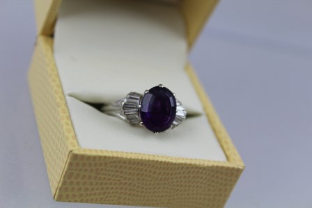 AN AMETHYST AND DIAMOND CLUSTER RING having central oval step cut amethyst, approx 3.95ct with