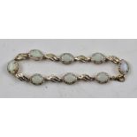 AN OPAL AND DIAMOND GOLD COLOURED METAL SET BRACELET, comprising eight oval cabochon opals, each