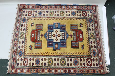 A TURKISH ELMAZ RUG having central yellow field with stylized geometric designs in blue, green,