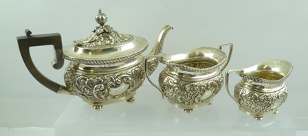 JOSEPH GLOSTER AN EDWARDIAN SILVER THREE PIECE BACHELOR TEA SET of Georgian design, repousse