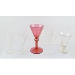 A 19TH CENTURY CRANBERRY WINE GLASS, having slice cut tapering bowl with engraved fruiting vine rim,