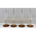 PAUL BAYLEY A SET OF FOUR ART GLASS GOBLETS with plain bowls on ridged stems and golden platform