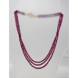 A BURMESE RUBY THREE-STRAND LIGHTLY GRADUATED NECKLET of multiple faceted cut rubies and generous