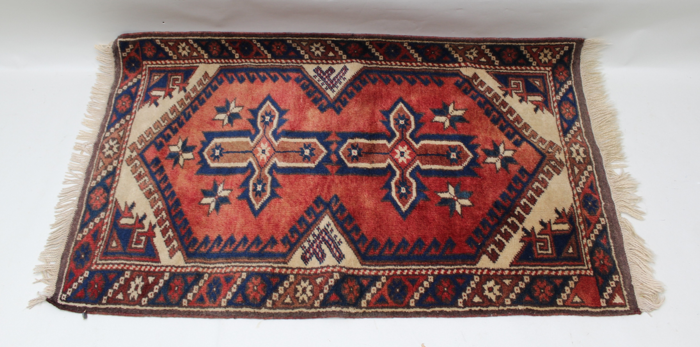 A TURKISH VILLAGE DOSEMEALTI RUG, having brick red field, with stylized geometric decoration,