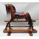 A LATE 20TH CENTURY TRESTLE DESIGN ROCKING HORSE having carved polished wood body with horse hair