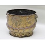 A GEORGE III EMBOSSED BRASS COAL BIN with lion mask ring handles, decorated with armorials and fleur