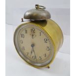AN "ANSONIA" USA BRASS CASED ALARM CLOCK, bell mounted to top, with ring handle, the dial with