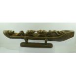 AN AFRICAN CARVING OF A CANOE containing stylised figures in various poses, 64cm long, complete with