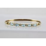 A GOLD COLOURED METAL BANGLE set five oval topaz with simulated diamonds between