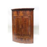 AN EARLY 19TH CENTURY MAHOGANY TWO DOOR WALL HANGING CORNER CABINET, the frieze with acorn