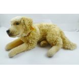 A STEIFF MOHAIR DOG in lying position, button and yellow tag in ear, wearing a leather collar,