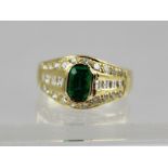 A GOLD COLOURED METAL EMERALD AND DIAMOND SET CLUSTER RING, having large rectangular emerald