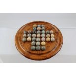 A TURNED YEW-WOOD SOLITAIRE BOARD 20cm diameter, together with a SET OF STONE MARBLES