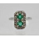 AN ART DECO STYLE EMERALD AND DIAMOND SET RING, having two circular emeralds surrounded by