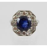 A WHITE GOLD COLOURED METAL SAPPHIRE AND DIAMOND CLUSTER RING having single large sapphire