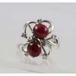 A RUBY AND DIAMOND RING, having two cabochon rubies in a modernist setting with five interspersed