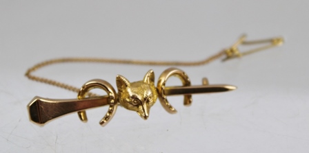 A VICTORIAN GOLD HUNTING BAR BROOCH fashioned with a fox mask and two horse shoes on a horse shoe