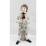 A LATE 19TH CENTURY CONTINENTAL PORCELAIN TAPER HOLDER MODELLED AS A BOY, standing beside an open