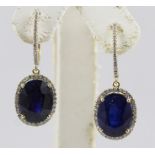 A PAIR OF 14CT GOLD, SAPPHIRE AND DIAMOND EARRINGS, each having a large sapphire bordered by small