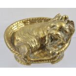 A CAST BRASS ORNAMENT OF A LAP DOG possibly a Pekinese, curled up in a basket, 15cm wide