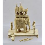 A CIRCA 1900 INDIAN CARVED IVORY ELEPHANT with howdah and figures, on a platform base, 13cm high