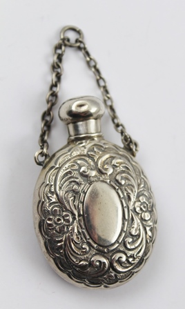 GEORGE UNITE A SILVER SCENT FLASK of oval form with screw cap and chain handle, embossed floral