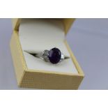 AN AMETHYST AND DIAMOND CLUSTER RING having central oval step cut amethyst, approx 3.95ct with