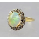 AN OPAL AND DIAMOND CLUSTER RING, having central large opal surrounded by diamonds, on gold coloured