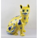 A "MOSANIC" GALLE STYLE POTTERY SEATED CAT, yellow ground with hand painted blue decoration, inset