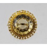 A VICTORIAN 15CT GOLD CITRINE BROOCH, having circular central large stone within a decorative rope