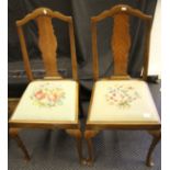 Two reproduction mahogany chairs with embroidered seats.