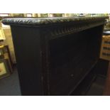 A large stained oak bookcase with carved panel and cornice decoration.