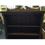 A large oak bookcase with decorative panels, dental moulding and scrolling volutes with floral