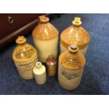 A selection of salt glazed stone bottles with various advertisements.