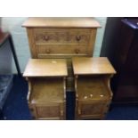 A golden oak chest of drawers and two bed side tables.