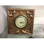 An arts and crafts mantle clock with copper front in art nouveau design.