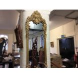 *A tall wall mirror with a gilded wooden Classical and flower design frame.